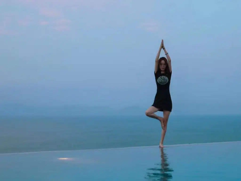 Guest practicing yoga by infinity pool with ocean view at dive resort in Bali