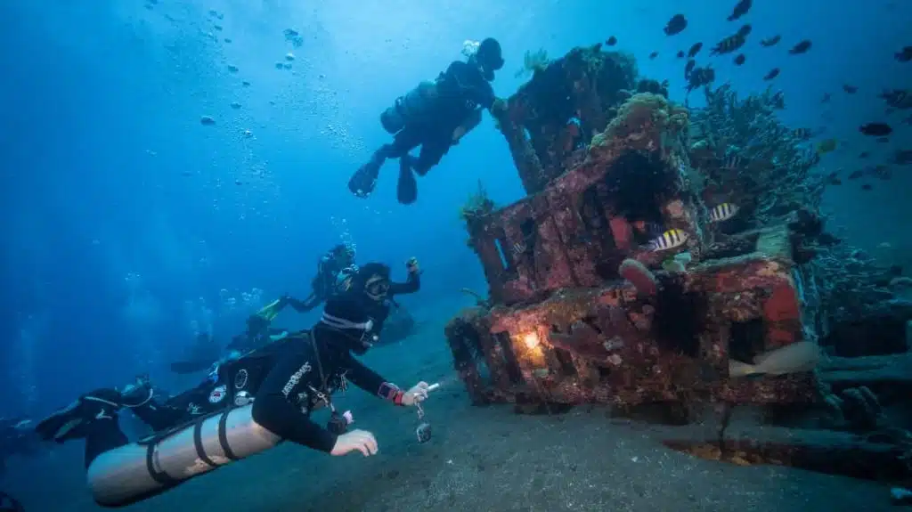 Pyramids/ Jemeluk Bay with divers holding underwater cameras and lights