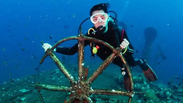 Scuba diver exploring the USAT Liberty Wreck in Tulamben Bali at Amed dive site