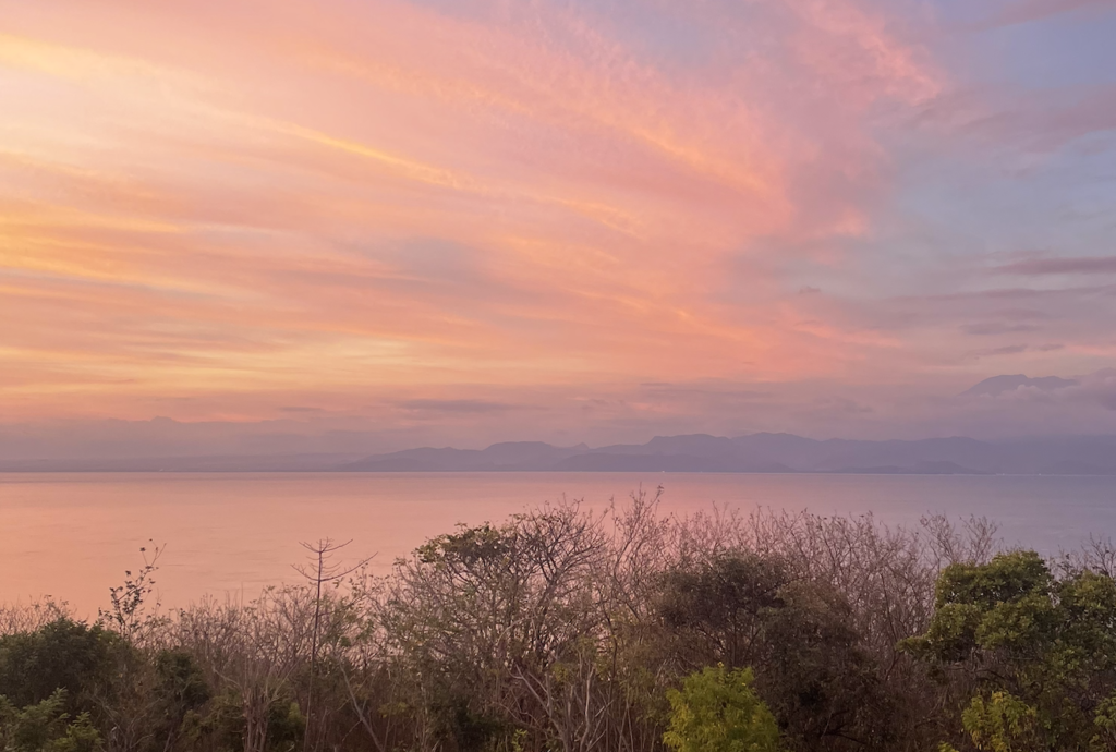 Sunset sky over Nusa Penida coastline with soft pink and orange clouds
