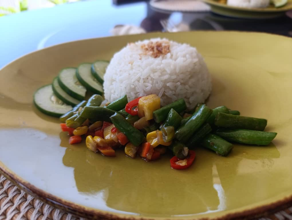 Steamed white rice served with stir fried vegetables and fresh cucumber slices