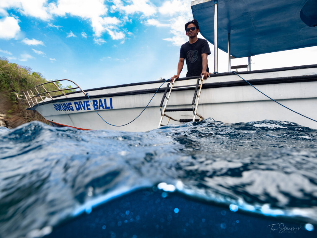 Jukung Dive Bali boat with dive guide preparing for entry in clear blue waters of Nusa Penida