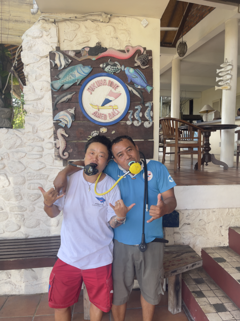 Happy PADI Open Water divers celebrating scuba certification at Jukung Dive Resort in Nusa Penida, Bali, after completing their dive course.