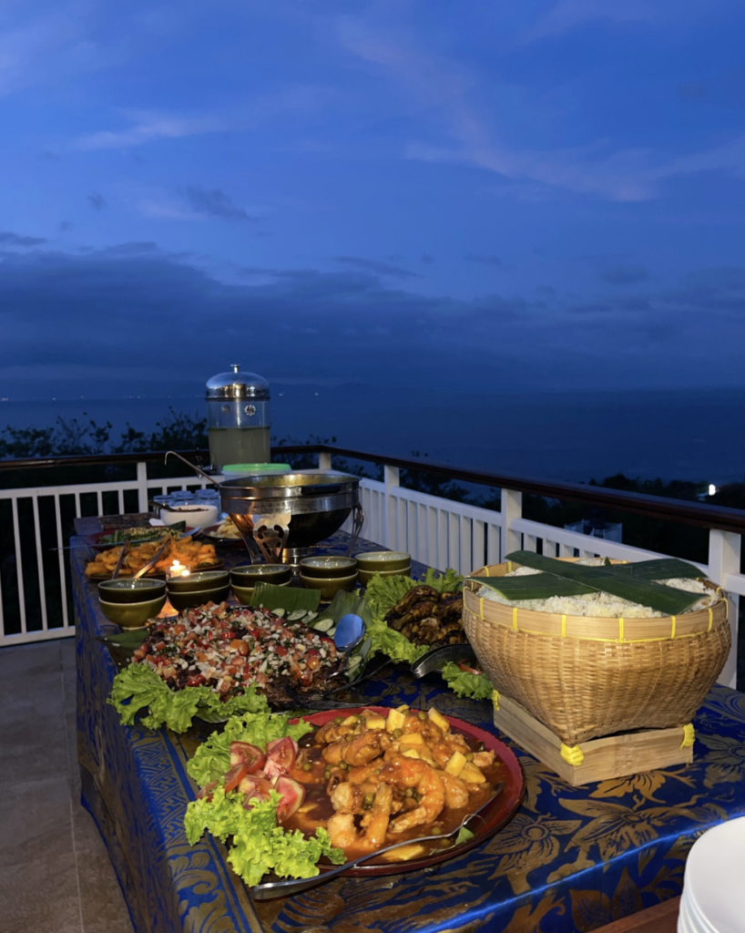 Seafood barbecue dinner at Sky Penida Rooftop Restaurant with panoramic sunset views overlooking the ocean and Mount Agung in Bali.