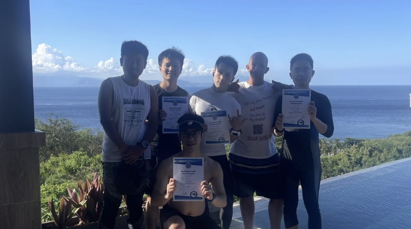 Newly certified PADI Open Water divers celebrating their certification at Jukung Dive Resort Nusa Penida, Bali, after completing their scuba diving course.