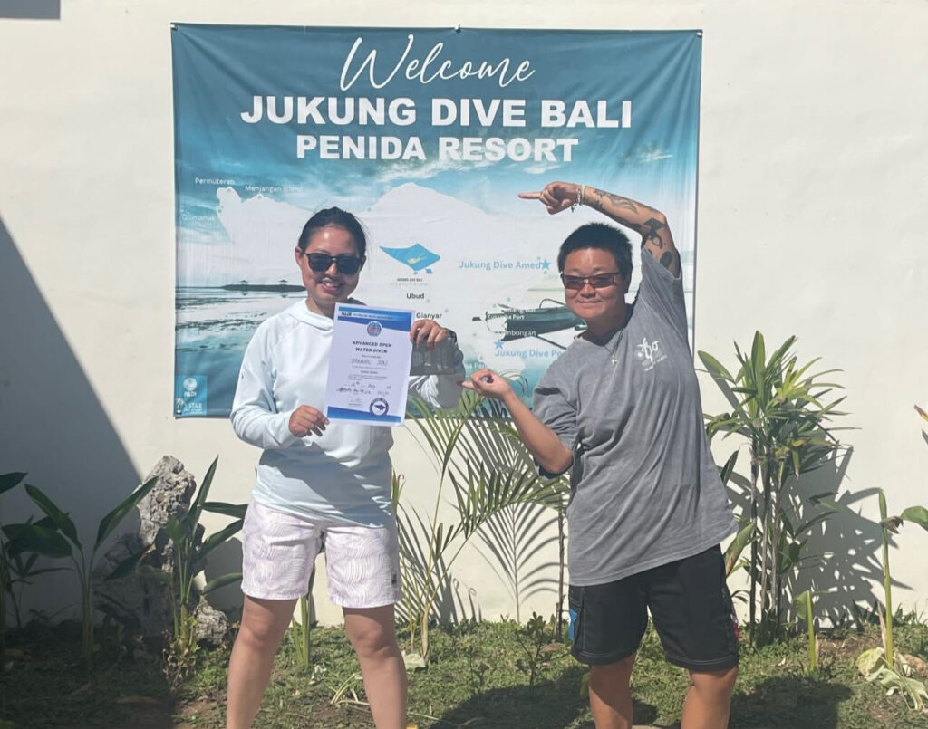 Newly certified PADI Open Water diver celebrating course completion with instructor at Jukung Dive Resort in Nusa Penida, Bali.