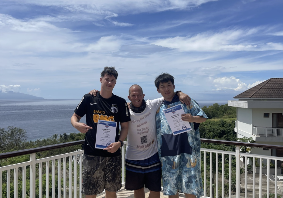 New PADI Open Water Divers celebrating their scuba diving certification at Jukung Dive Resort in Nusa Penida, Bali.