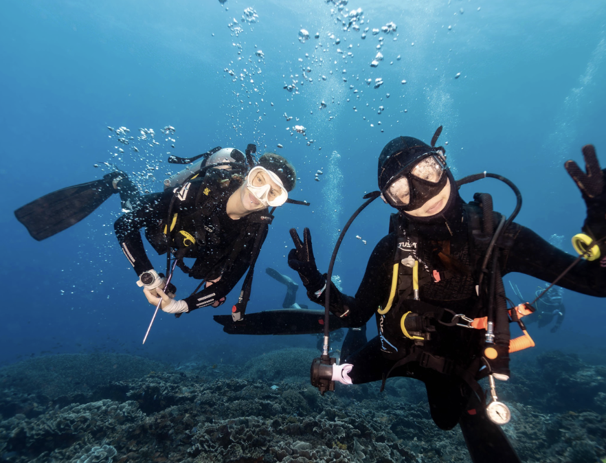Happy first-time scuba divers posing underwater during a PADI Discover Scuba Diving course in Nusa Penida, Bali