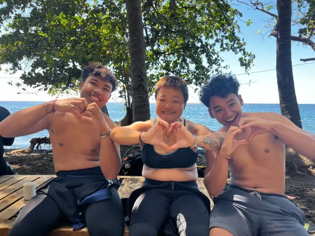 Three Jukung Dive staff showing love with hands looking happy after dive